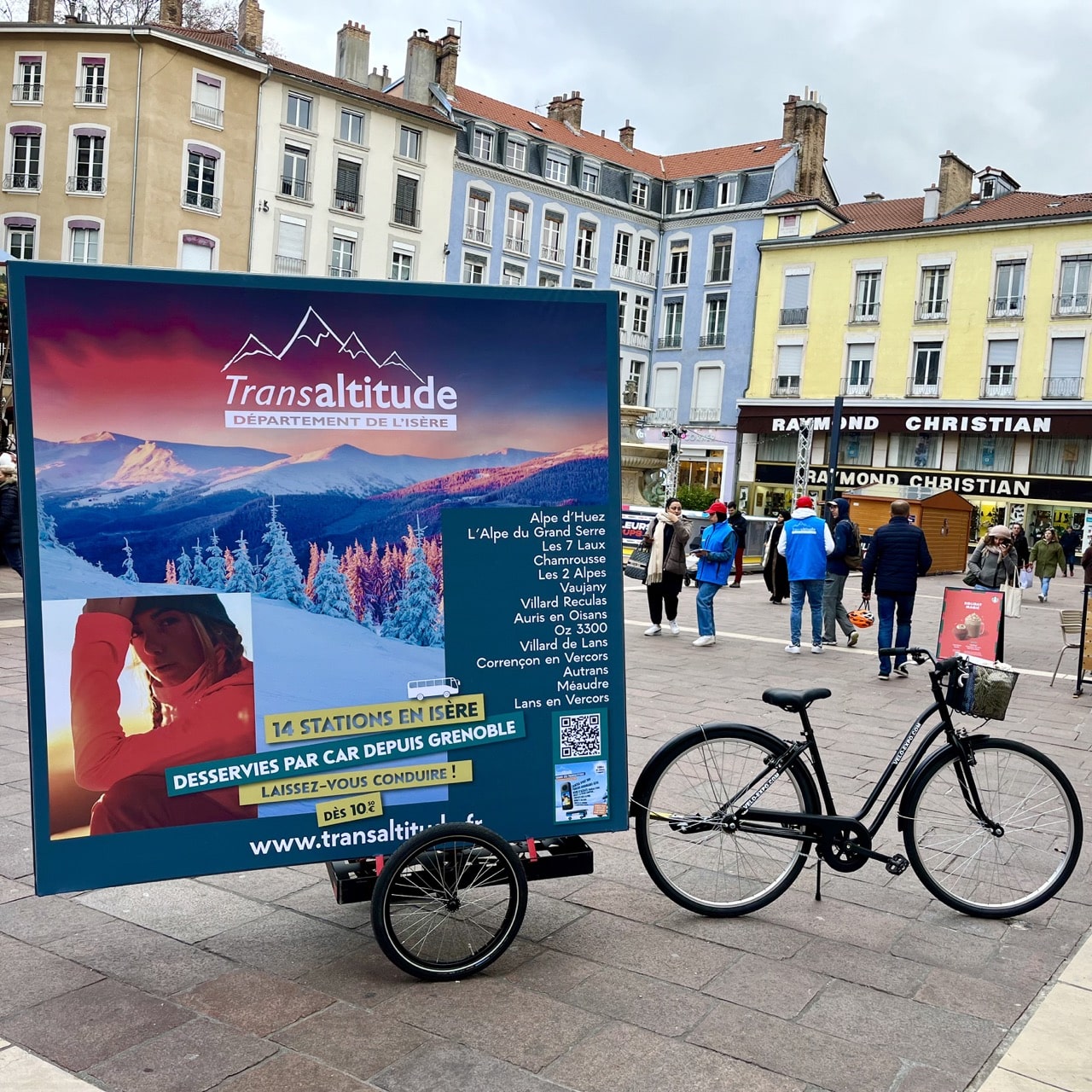 Place Grenette Grenoble. Velo Expo VFD TransAltitude à Grenoble France. Affichage mobile, animation drive-to-web, distribution de flyers avec vélo triporteur et remorque affichage mobile cube grand format. Campagne communication ooh hors-media par activation affichage mobile digital avec vélo triporteur publicitaire street marketing | Velo Expo | Agence Veymont