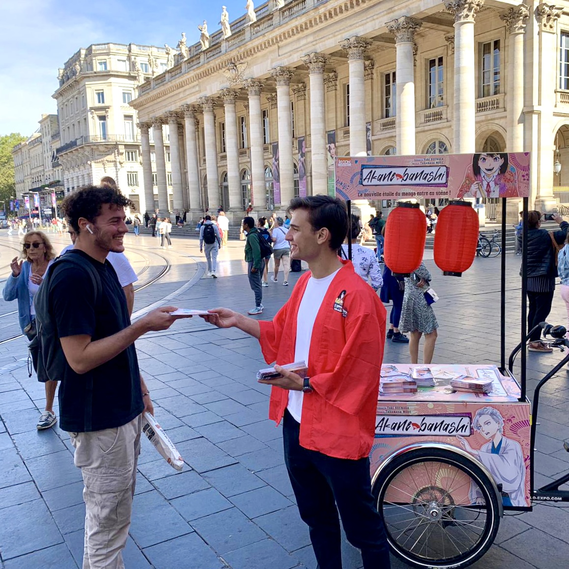 Velo Expo KI-00N à Bordeaux place de la Comédie. Campagne de communication et promotion de Akane-banashi par la distribution d'échantillons avec vélo publicitaire triporteur peronnsalisés. Campagne communication ooh hors-media par activation affichage mobile digital avec vélo triporteur publicitaire street marketing | Velo Expo | Agence Veymont