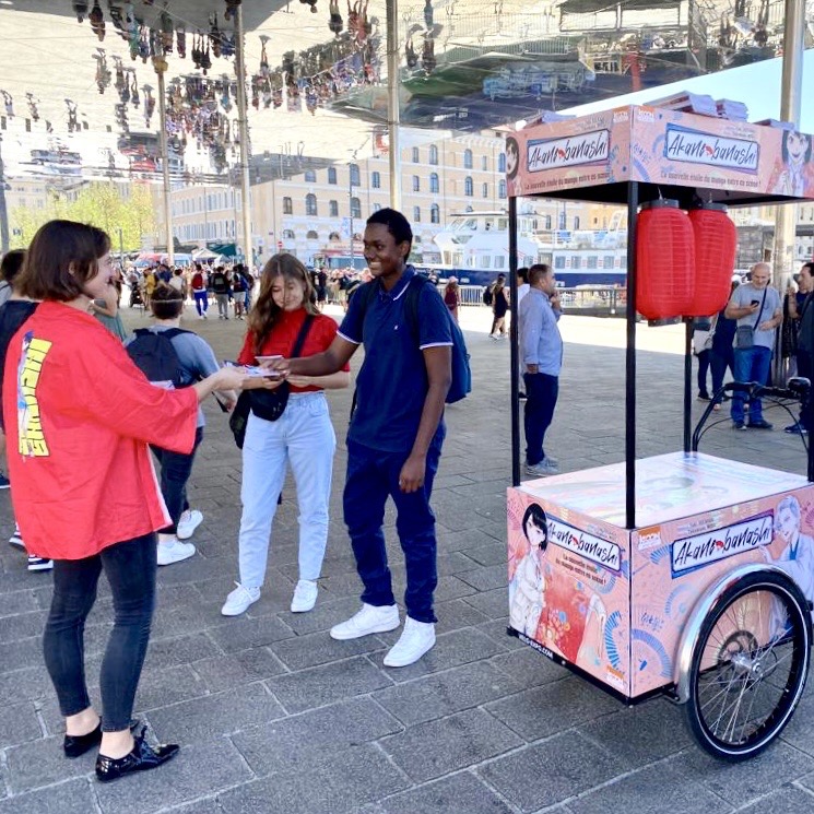 Vieux Port. Marseille. Velo Expo KI-00N. Campagne de communication et promotion de Akane-banashi par la distribution d'échantillons avec vélo publicitaire triporteur personnalisés. Campagne communication ooh hors-media par activation affichage mobile digital avec vélo triporteur publicitaire street marketing | Velo Expo | Agence Veymont